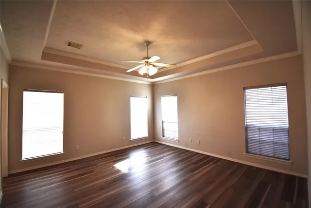 an empty room with wooden floor chandelier and windows