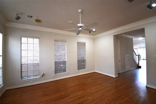 a view of an empty room with wooden floor and a window
