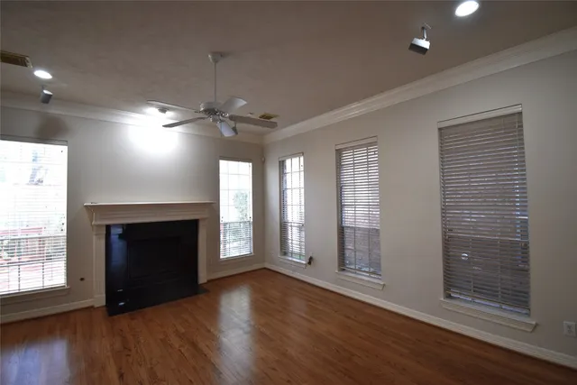 a view of an empty room with wooden floor fireplace and a window