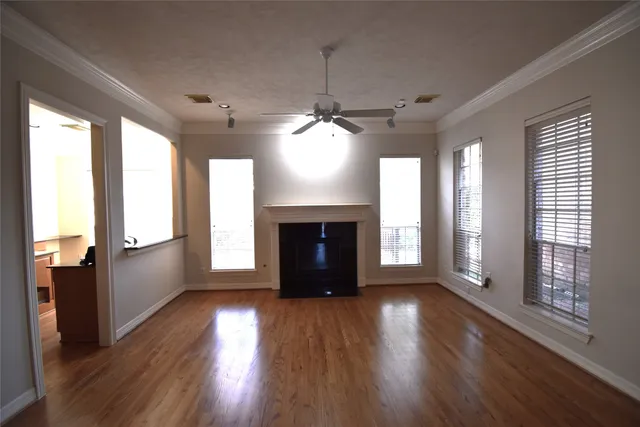 an empty room with wooden floor fireplace and windows