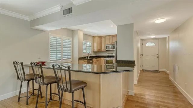 a kitchen with stainless steel appliances kitchen island granite countertop a table chairs in it and wooden floors