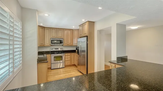 a kitchen with stainless steel appliances granite countertop a stove a sink and a refrigerator