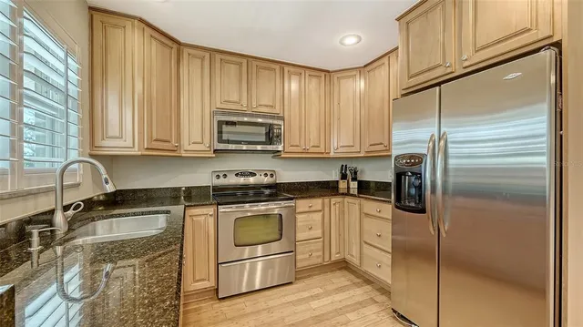 a kitchen with granite countertop a refrigerator sink and cabinets