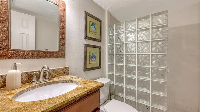 a bathroom with a granite countertop sink a mirror and a toilet
