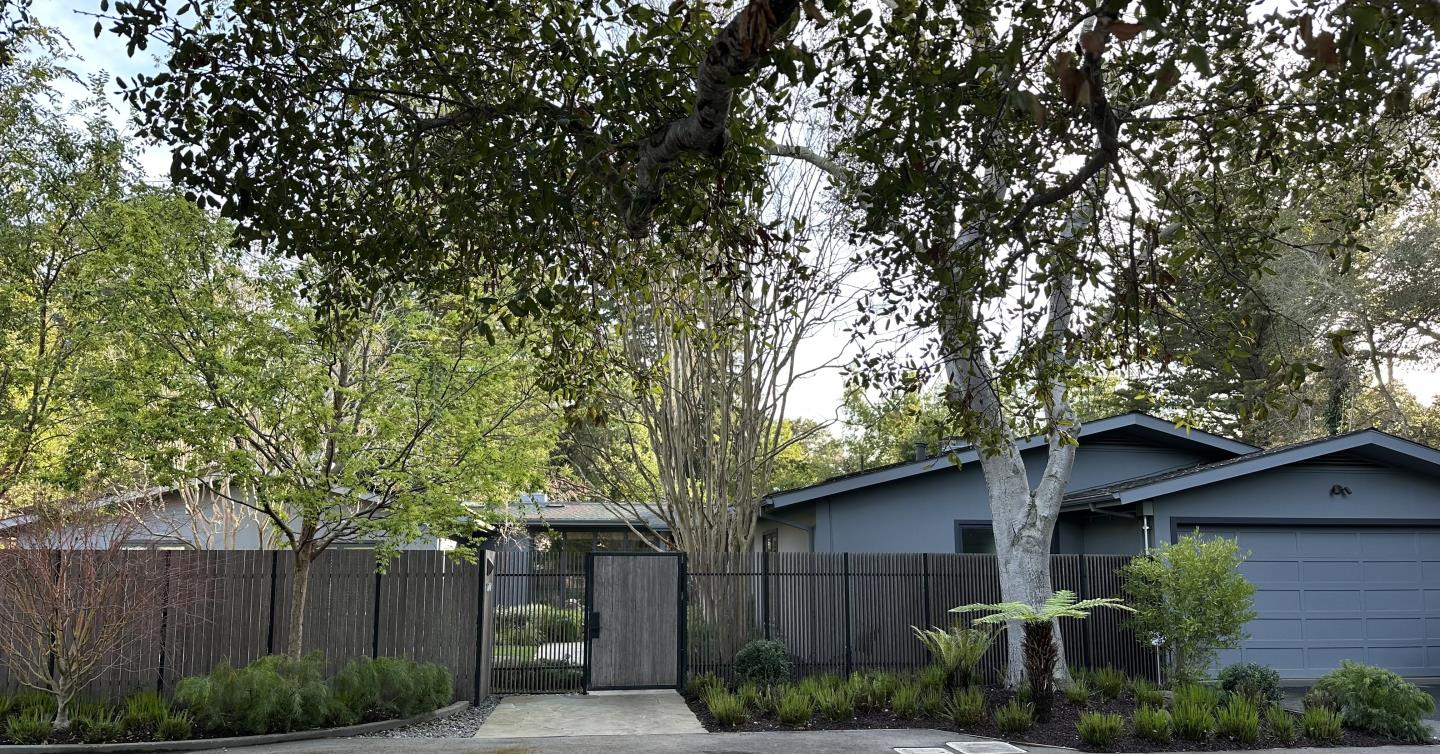 a small barn in front of a tree with wooden fence