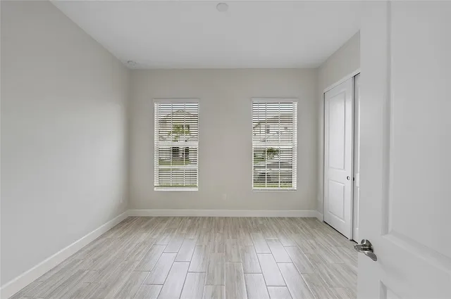 an empty room with wooden floor and windows