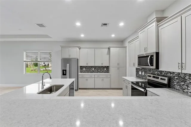a kitchen with stainless steel appliances a stove a refrigerator a sink a stove and white cabinets