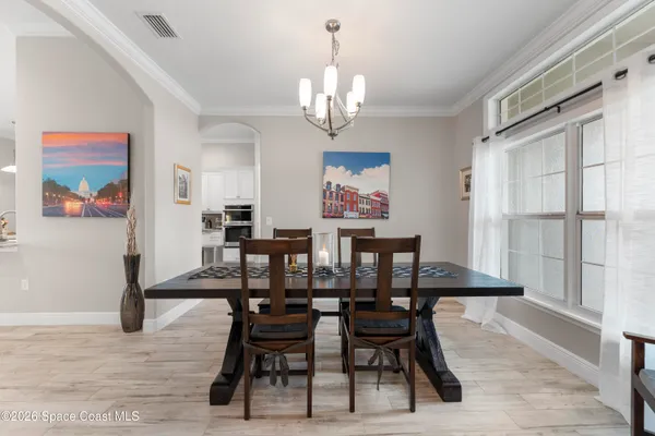 a view of a dining room with furniture a chandelier and wooden floor