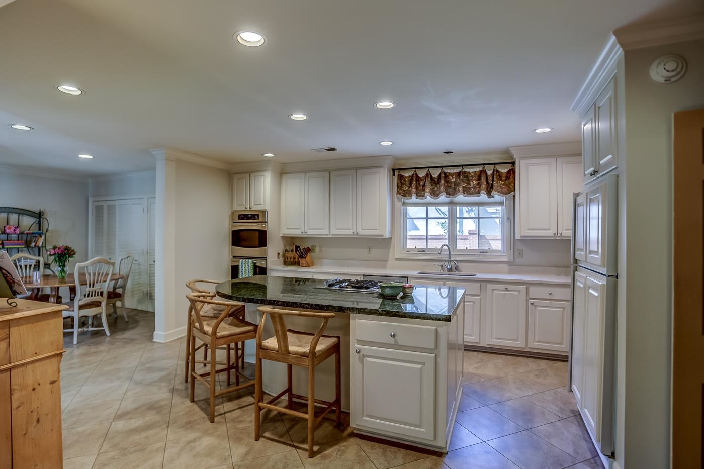 4481 Barfield Road Memphis, TN 38117 - Photo 11 of 32 a kitchen with kitchen island granite countertop wooden cabinets and center island with chairs