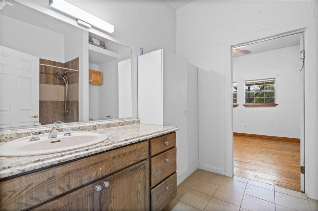 555 Harmon Hills Road, Unit A Dripping Springs, TX 78620 - Photo 19 of 29 A classic bathroom vanity with a spacious counter and ample storage, complementing the adjacent hardwood flooring.