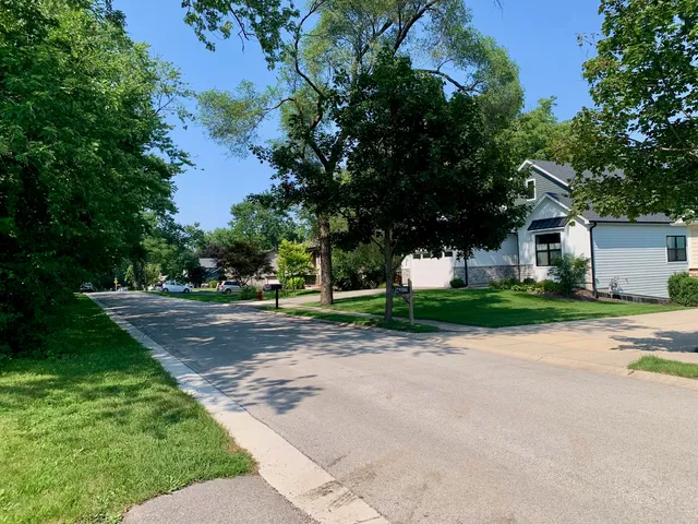 a view of a house with a big yard and large trees
