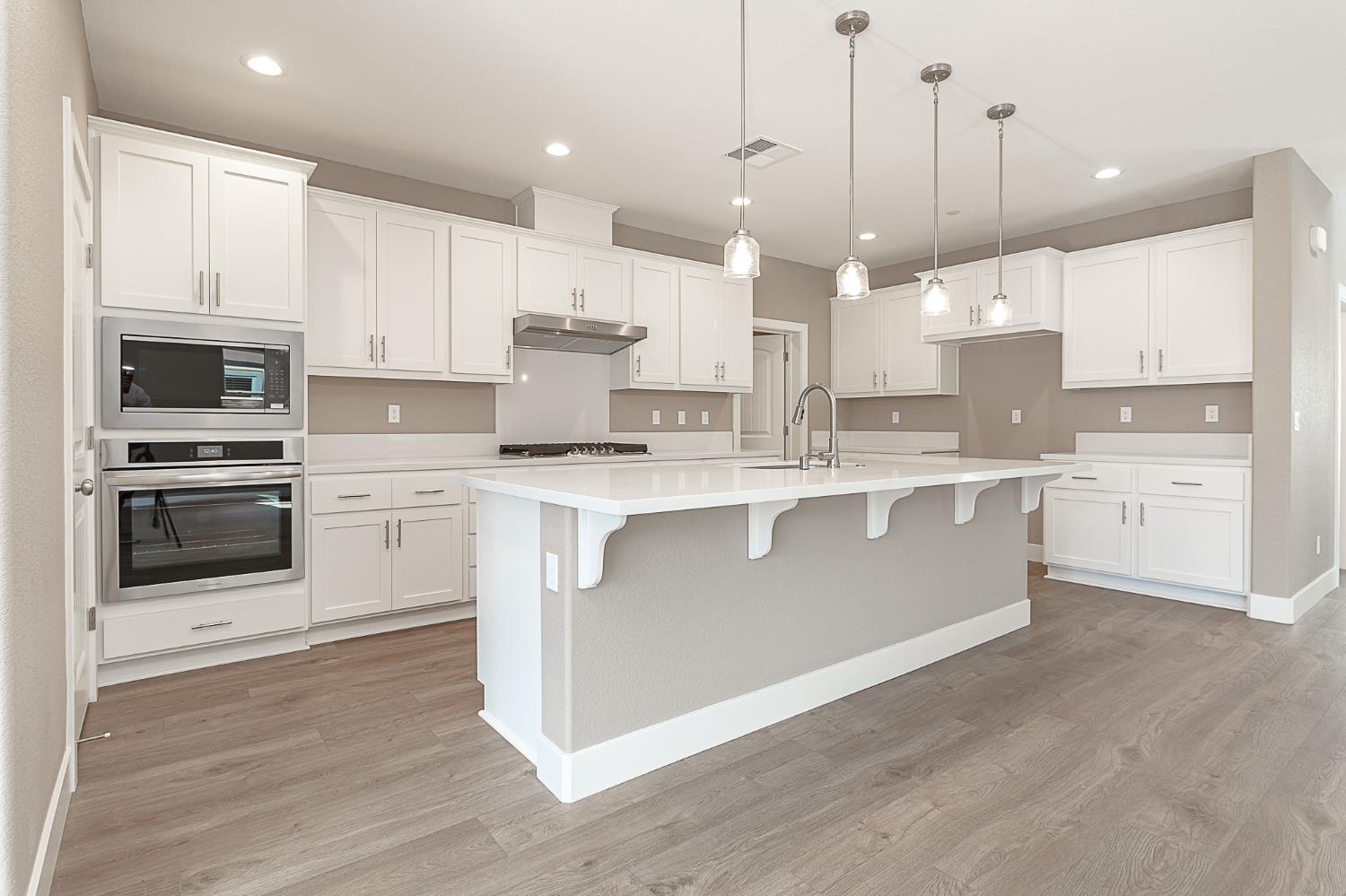 1310 Veteran Street Manteca, CA 95337 - Photo 11 of 33 a large kitchen with stainless steel appliances granite countertop a stove a sink a refrigerator and white cabinets with wooden floor