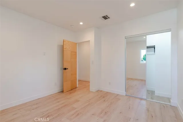 an empty room with wooden floor and mirror