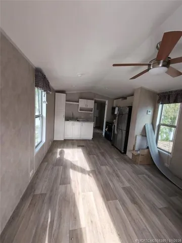 a view of empty room with wooden floor and fan