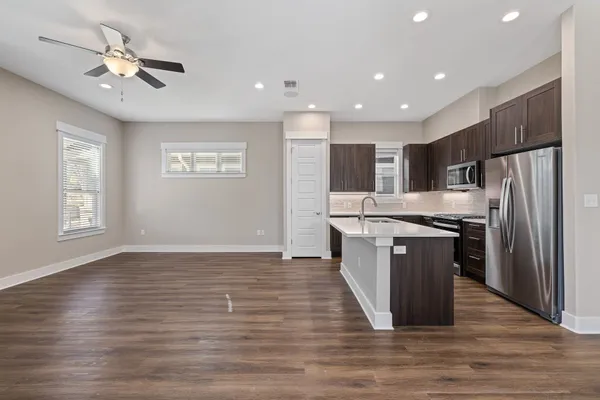 a kitchen with stainless steel appliances granite countertop a refrigerator a sink dishwasher a stove and a oven with wooden floor