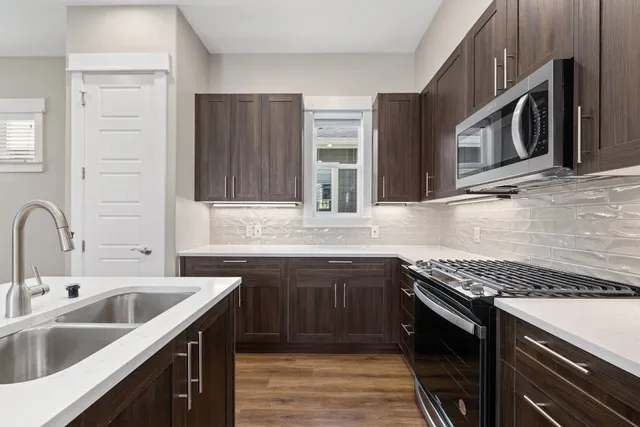 a kitchen with stainless steel appliances granite countertop a sink stove and cabinets