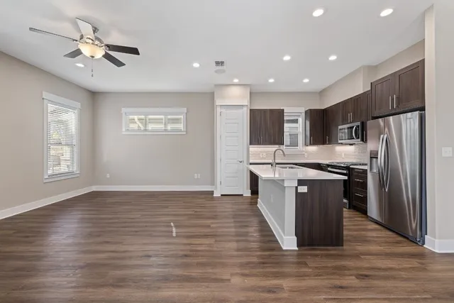 a kitchen with stainless steel appliances granite countertop a refrigerator a sink dishwasher a stove and a oven with wooden floor