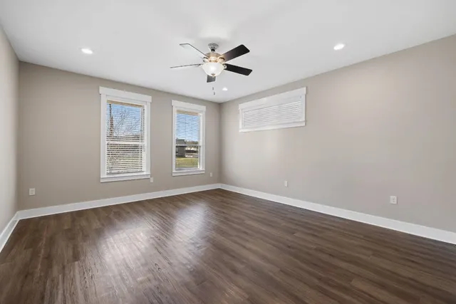 a view of an empty room with wooden floor and a window