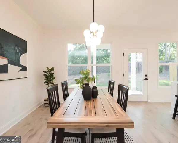 a view of dining room and livingroom with furniture wooden floor a rug a potted plant and a chandelier