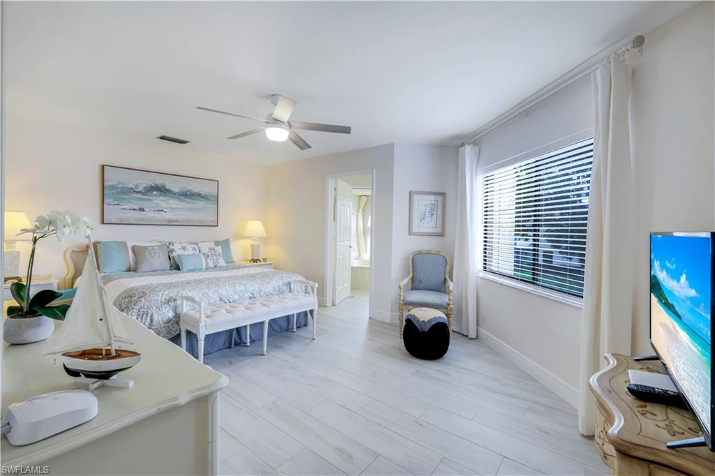 637 Beachwalk Circle, Unit E203 Naples, FL 34108 - Photo 11 of 30 a bedroom with a bed and a flat screen tv