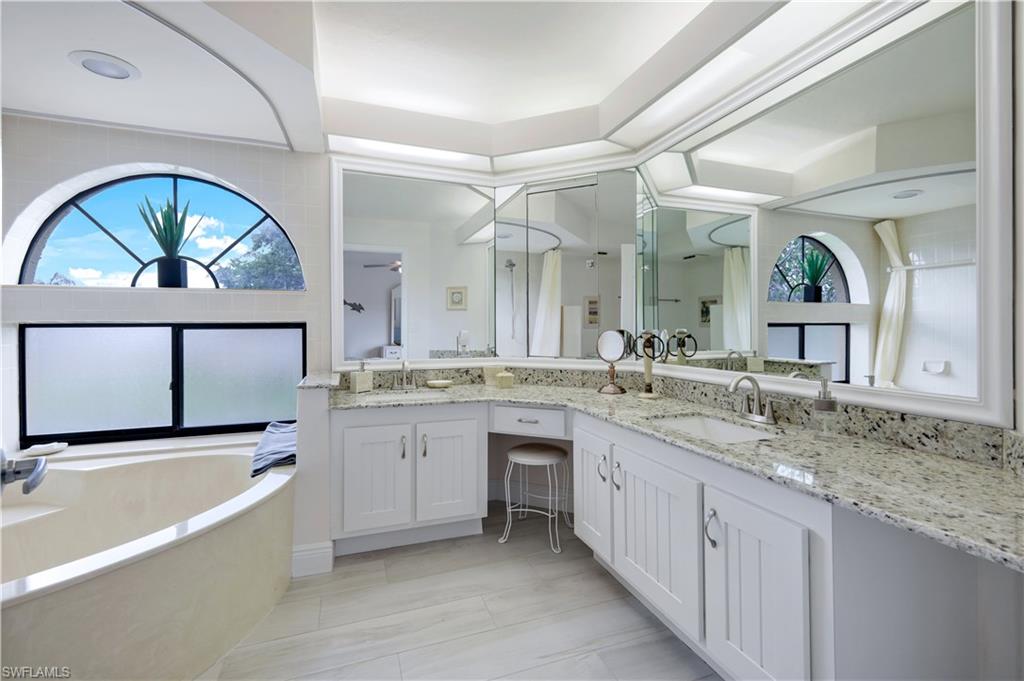 637 Beachwalk Circle, Unit E203 Naples, FL 34108 - Photo 13 of 30 a bathroom with a granite countertop bathtub a sink and a large mirror