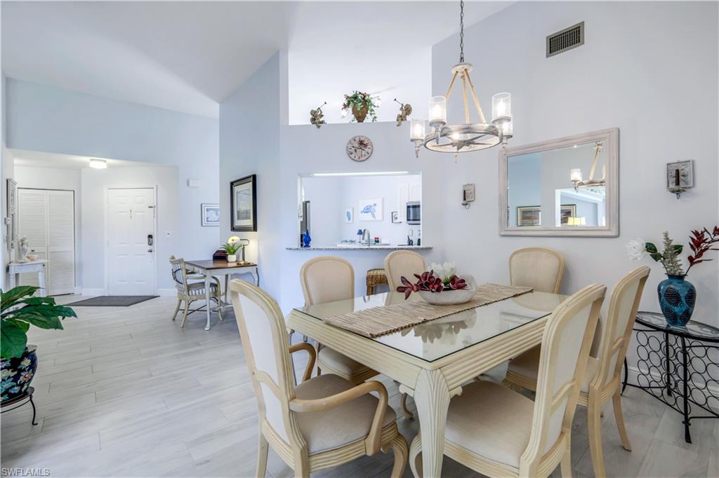 637 Beachwalk Circle, Unit E203 Naples, FL 34108 - Photo 10 of 30 a view of a dining room with furniture a chandelier and wooden floor