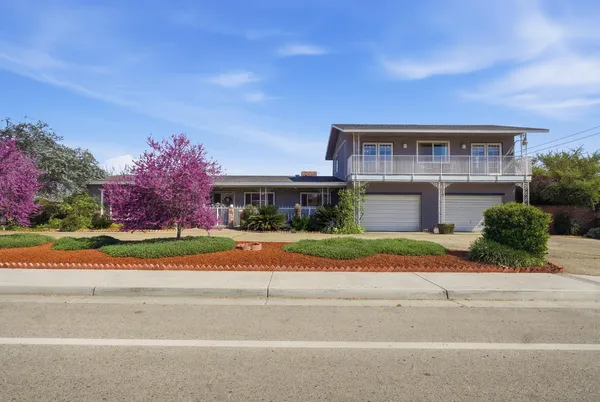 a front view of house with yard and trees in the background