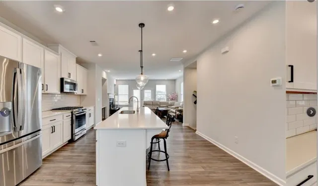 a kitchen with kitchen island a counter top space a sink stainless steel appliances and cabinets
