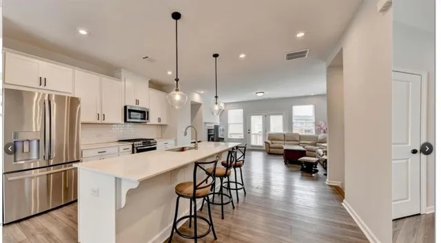 a kitchen with stainless steel appliances a stove a sink a center island and a refrigerator