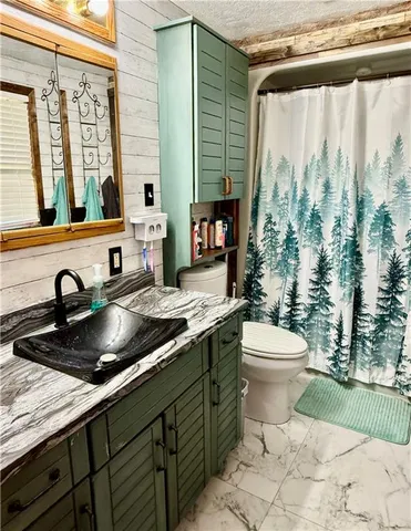 a bathroom with a granite countertop sink and a toilet