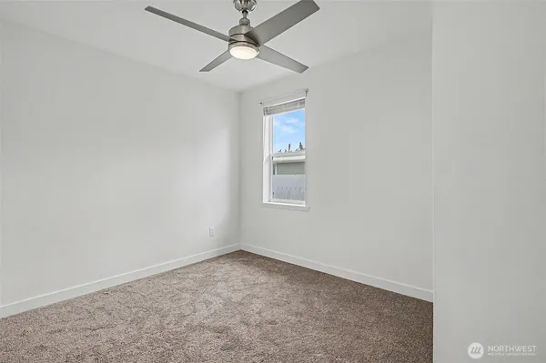 an empty room with a window and ceiling fan