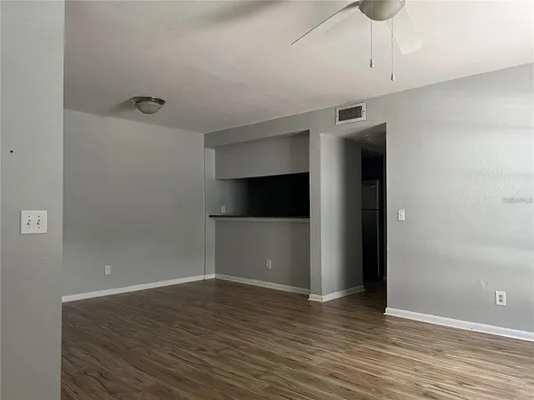 a view of an empty room with wooden floor and closet