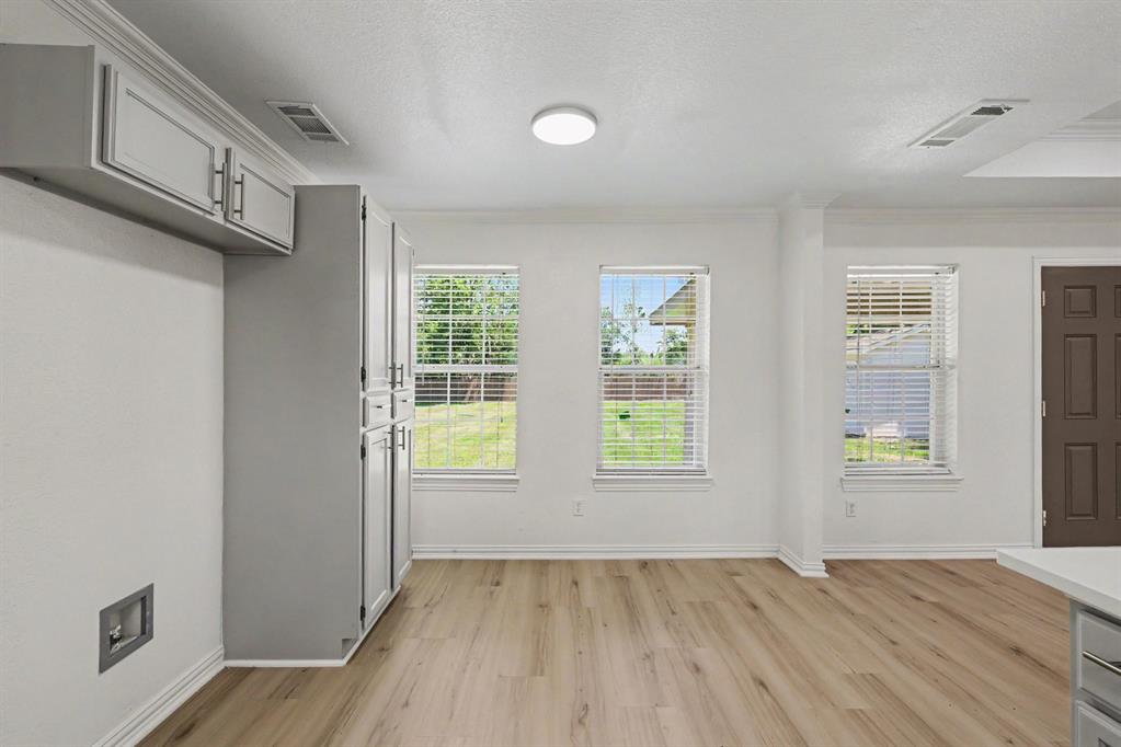 307 Dixon Street Terrell, TX 75160 - Photo 11 of 32 Spacious room featuring wood-finish flooring, multiple windows with blinds, and white baseboards