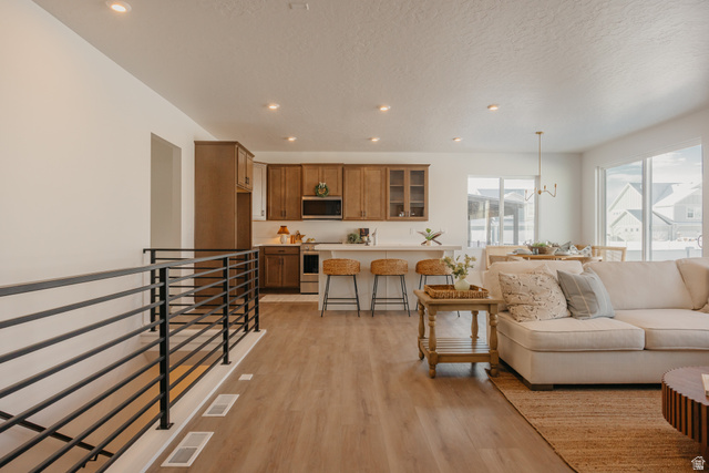 4595 North Fallow Way, Unit 511 Eagle Mountain, UT 84005 - Photo 2 of 32 Living room with light wood finished floors, suspended lighting, and a textured ceiling
