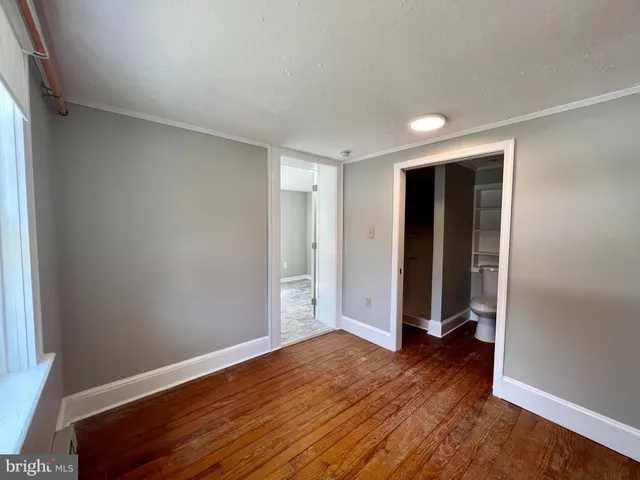 an empty room with wooden floor & window