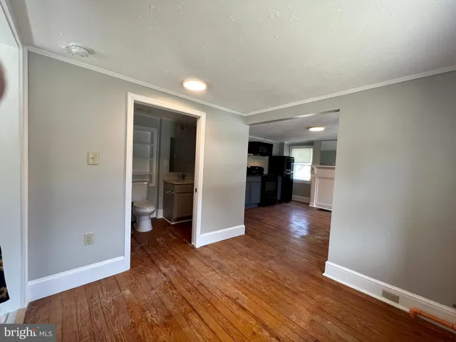 a view of an empty room with wooden floor and closet