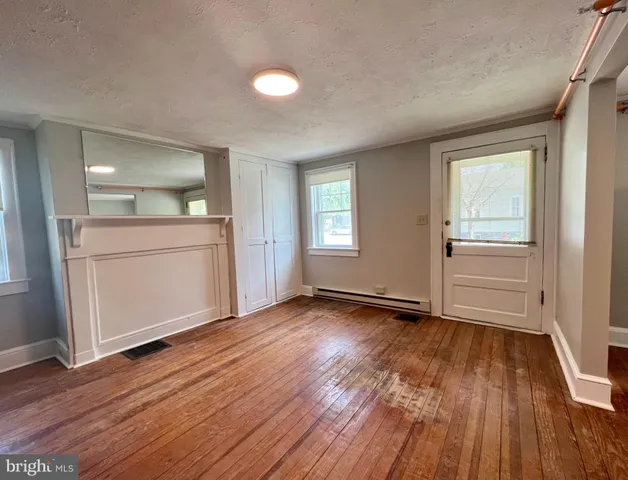 an empty room with wooden floor cabinet and windows