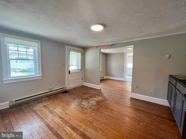 an empty room with wooden floor and windows