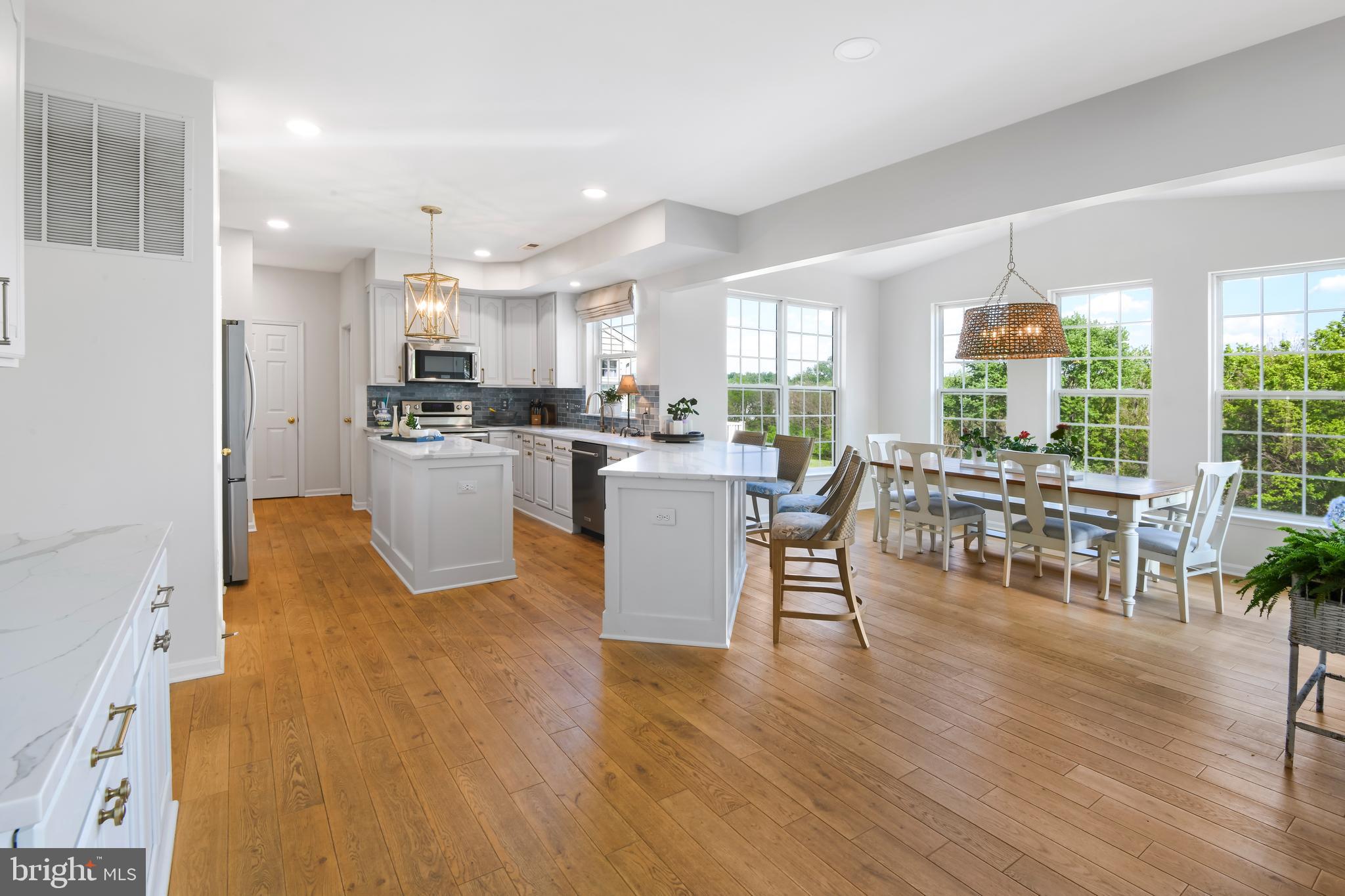 9105 Hendry Terrace Frederick, MD 21704 - Photo 8 of 51 a dining hall with stainless steel appliances granite countertop a stove top oven a dining table and chairs with wooden floor