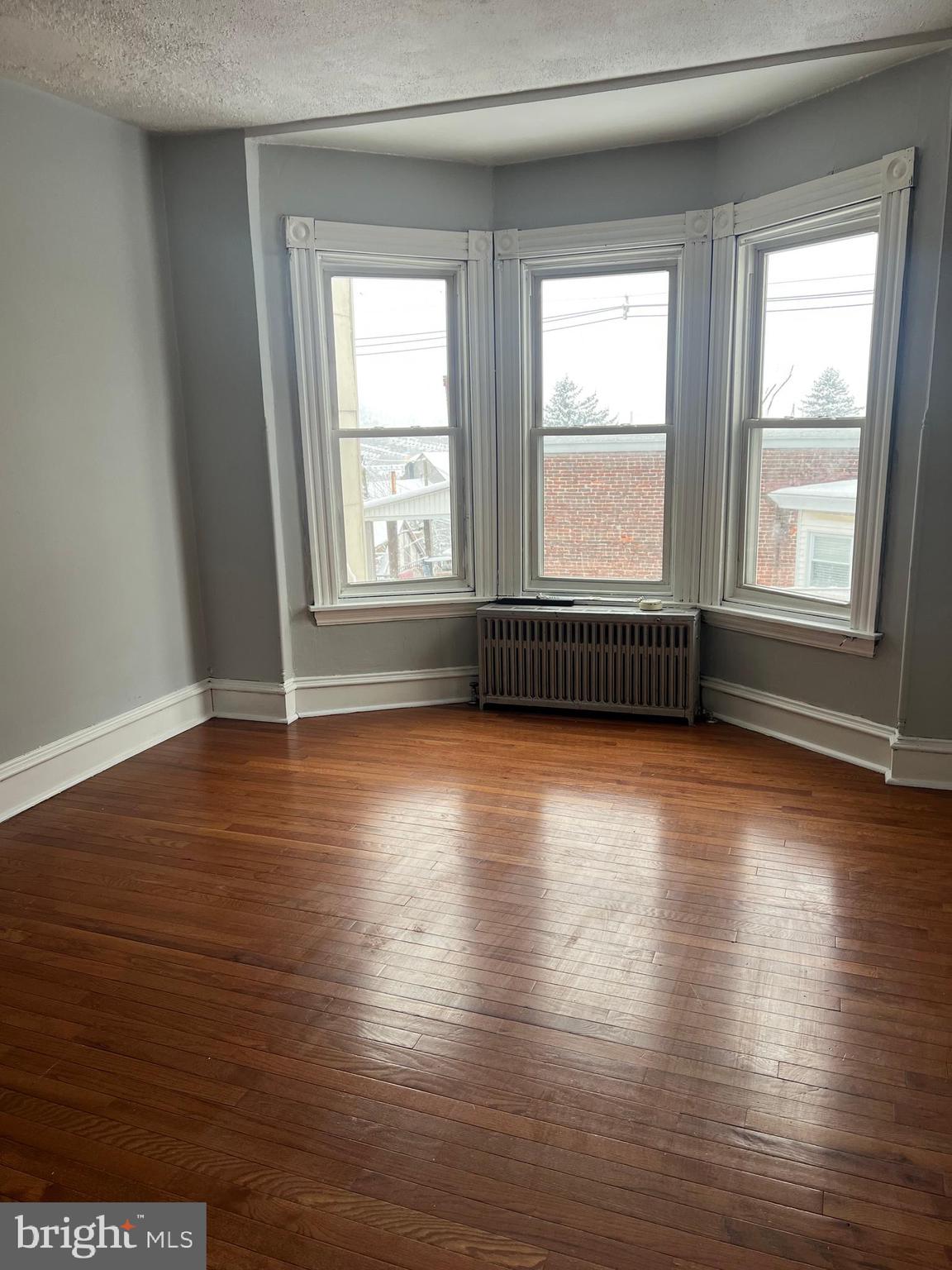 166 Clymer Street Reading, PA 19602 - Photo 6 of 7 an empty room with wooden floor and windows with curtains