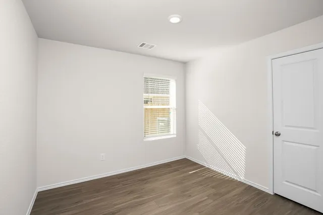 an empty room with wooden floor and window