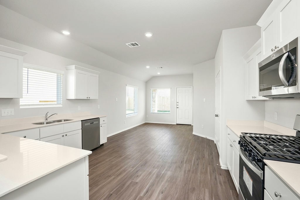 3075 Wild Indigo Trail Brookshire, TX 77423 - Photo 4 of 16 a kitchen with granite countertop a stove top oven a sink dishwasher and white cabinets with wooden floor