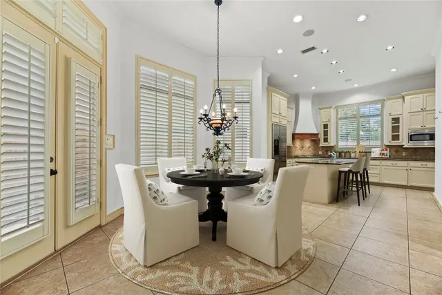 a kitchen with stainless steel appliances kitchen island granite countertop a refrigerator a sink a stove a dining table and chairs