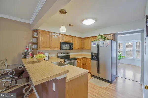 a kitchen that has a refrigerator a stove a sink and a dining table with wooden floor
