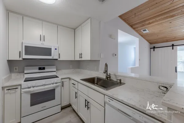 a kitchen with white cabinets and white appliances