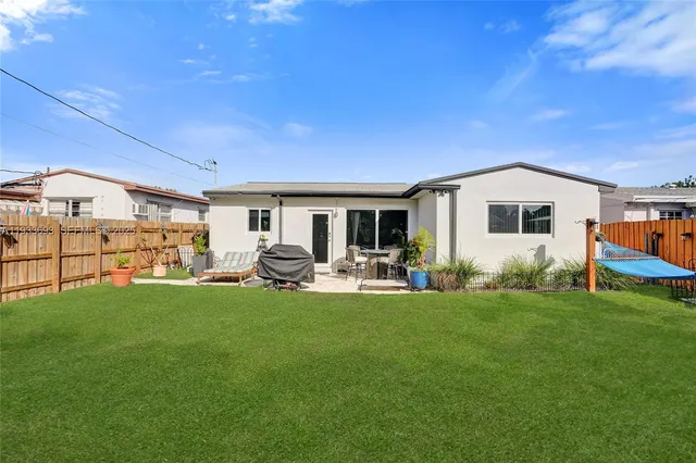 a view of a backyard with table and chairs potted plants and wooden fence