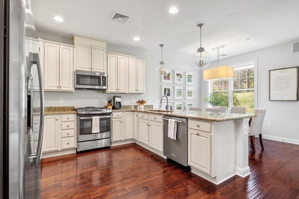 159 Hms Stayner Drive, Unit 159 Hingham, MA 02043 - Photo 5 of 35 a kitchen with stainless steel appliances a white stove top oven cabinets and a wooden floor