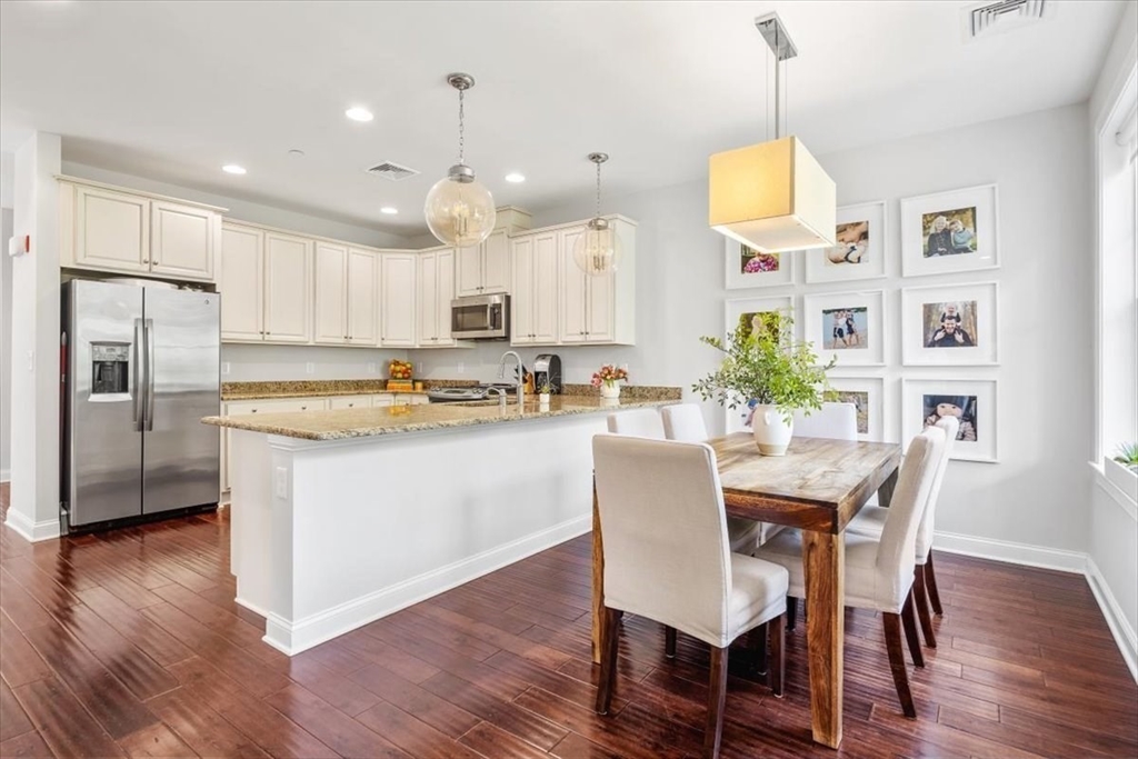 159 Hms Stayner Drive, Unit 159 Hingham, MA 02043 - Photo 6 of 35 a kitchen with stainless steel appliances granite countertop a refrigerator a stove a sink dishwasher and a dining table with wooden floor