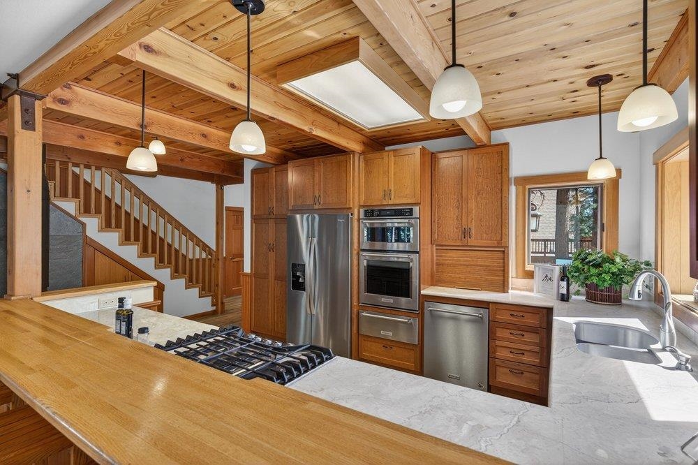 12964 Falcon Point Place Truckee, CA 96161 - Photo 13 of 28 a kitchen with stainless steel appliances kitchen island granite countertop a table chairs in it and wooden floors