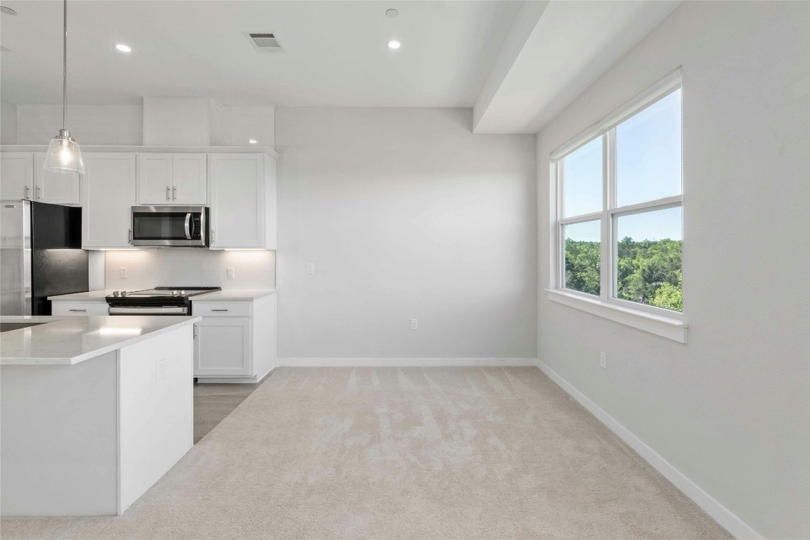 12001 Vista Parke Drive, Unit 702 Austin, TX 78726 - Photo 14 of 33 a kitchen with kitchen island a sink stainless steel appliances and window